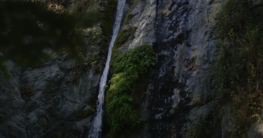 A narrow waterfall plunges down the side of a canyon