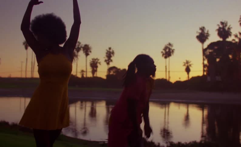 A man and woman perform a modern choreographed dance in front of a pond