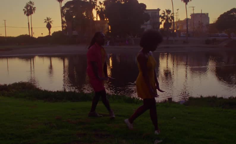 A man and woman dance in front of a lake in a tropical location