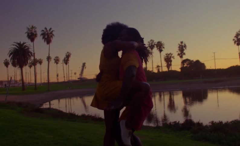 A man and woman dance in front of a pond