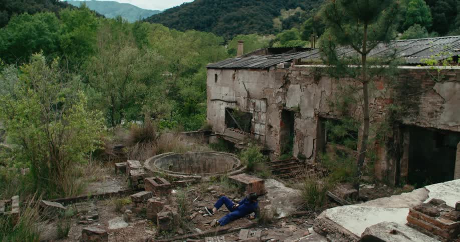 Man wearing virtual reality goggles wakes up on the ground next to a well on an abandoned building outdoors