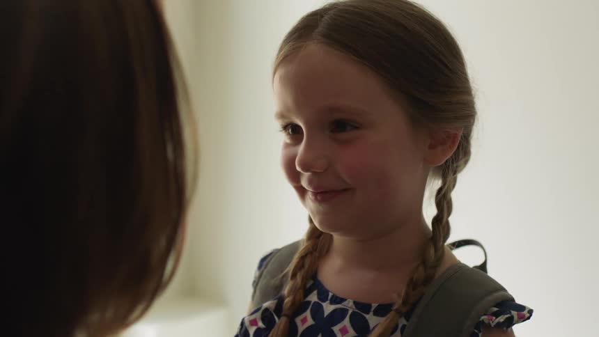 Mother preparing her daughter for school in the living room at home
