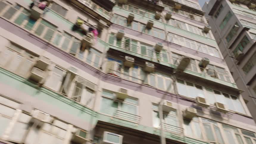 Pink and green apartment buildings sit side by side in a city