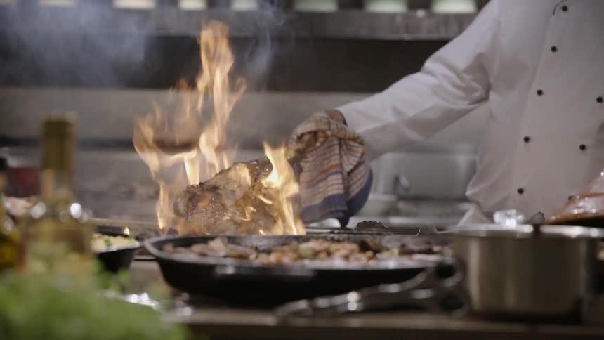 A chef is cooking a large piece of meat on a fire
