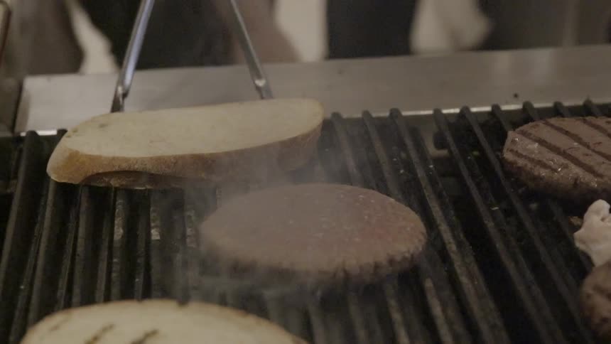 Burgers and buns are cooking on a grill