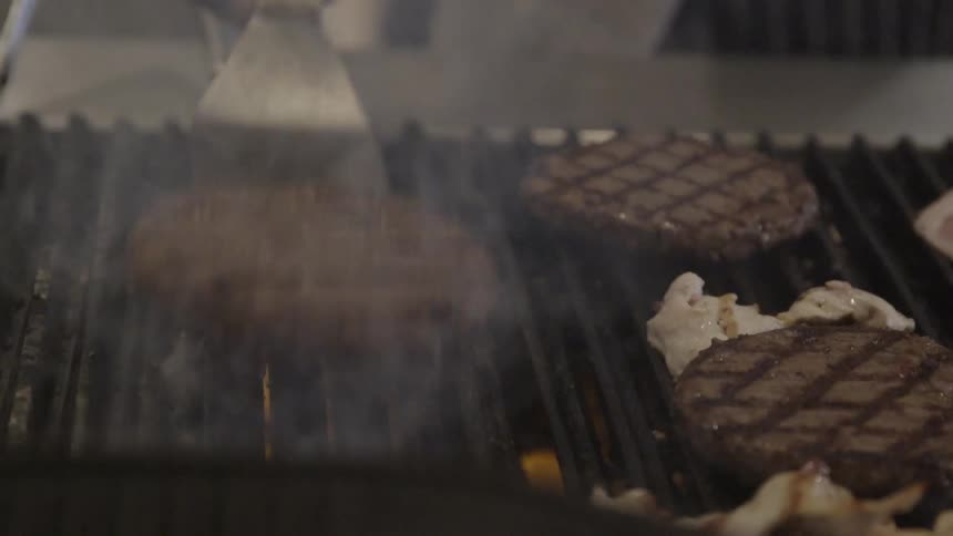 A spatula is used to turn meat on a grill
