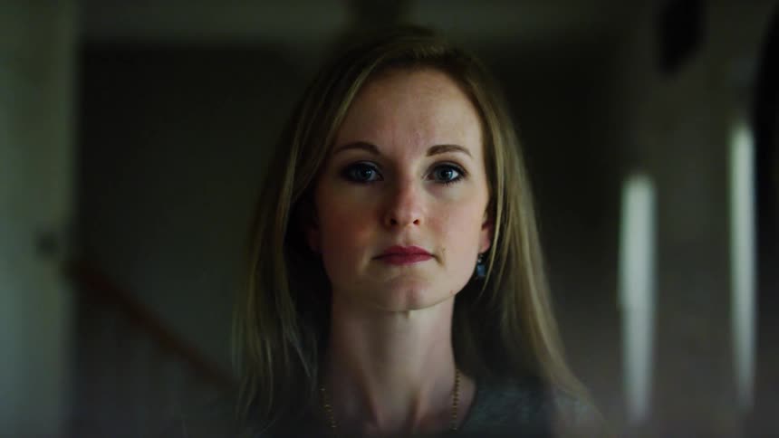 A woman is standing in a room next to a staircase