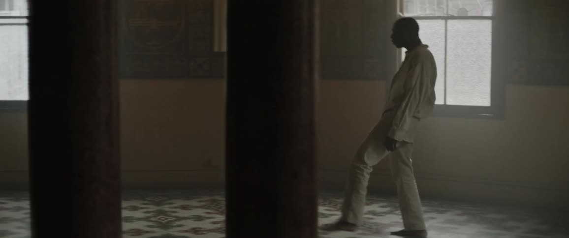 Reversed footage of a young man wearing a white shirt dancing on a dimly lit room