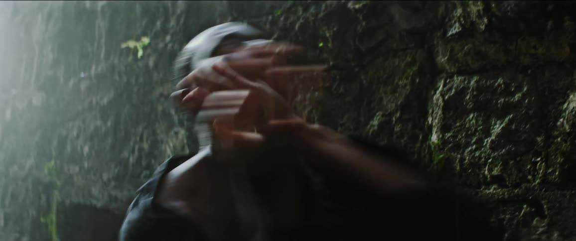 Male dancer dances near moss covered rock wall on misty day