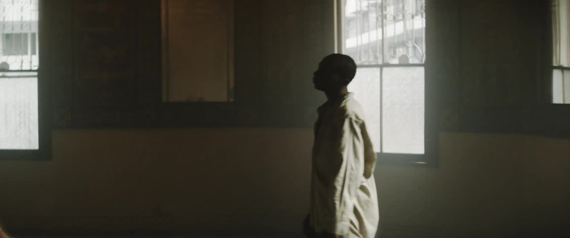Woman in a short black dress dancing with a man dressed in white inside a dimly lit room