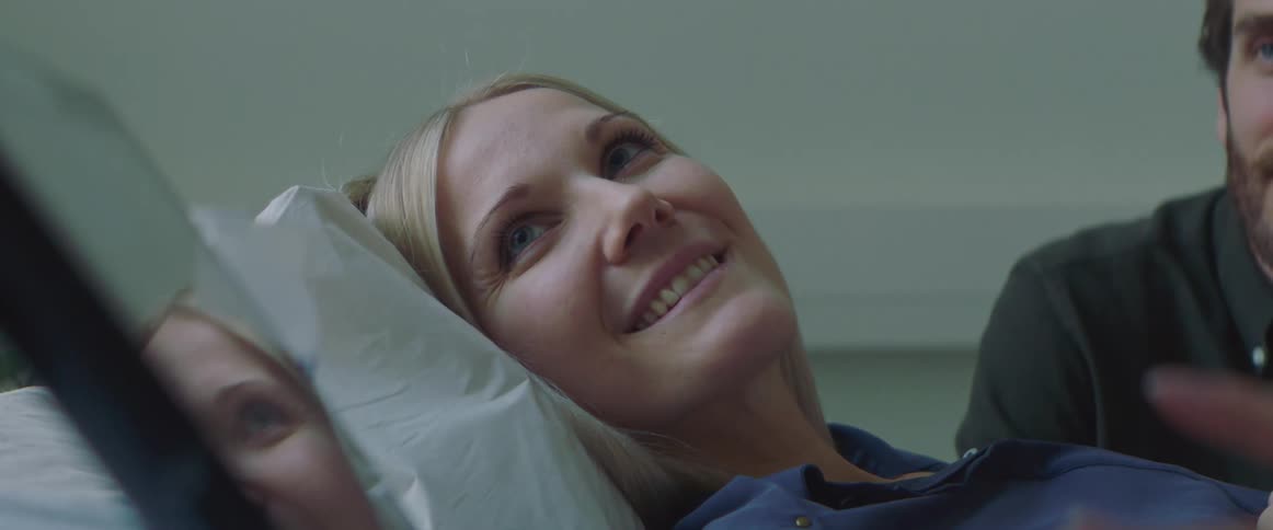 Happy hopeful expecting woman resting on a hospital bed looking at a screen