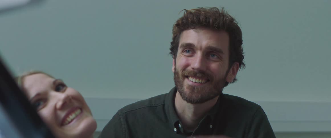 A woman and man are looking over to the side and smiling