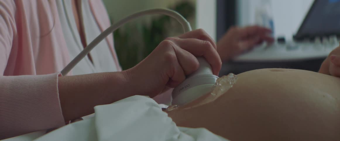 Close up of technician performing an ultrasound on a pregnant belly