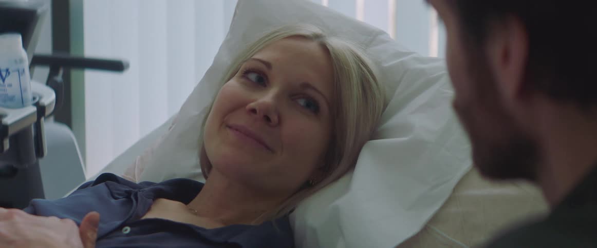 Calm woman resting on a hospital bed gets comforted by her couple
