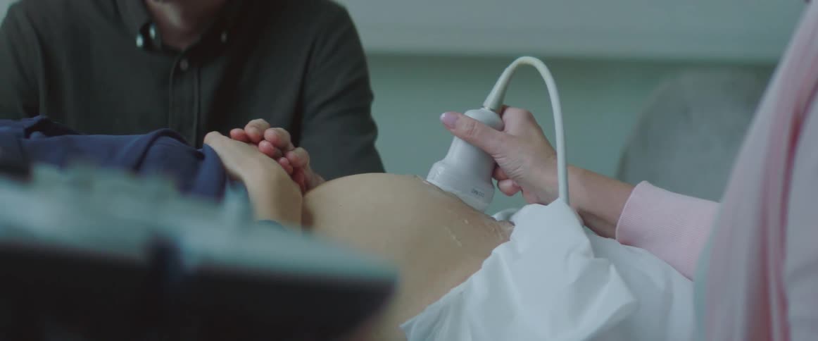 Pregnant couple staring lovingly at each other while getting an ultrasound
