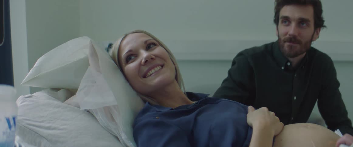 A pregnant woman smiles in the hospital bed