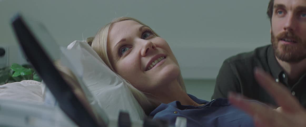 A woman smiles as she and her husband receive an ultrasound in a doctors office