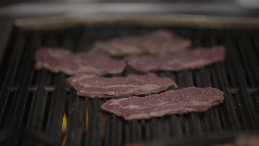 Steaks are cooking on a grill