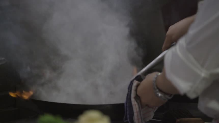 A chef is cooking food in a wok
