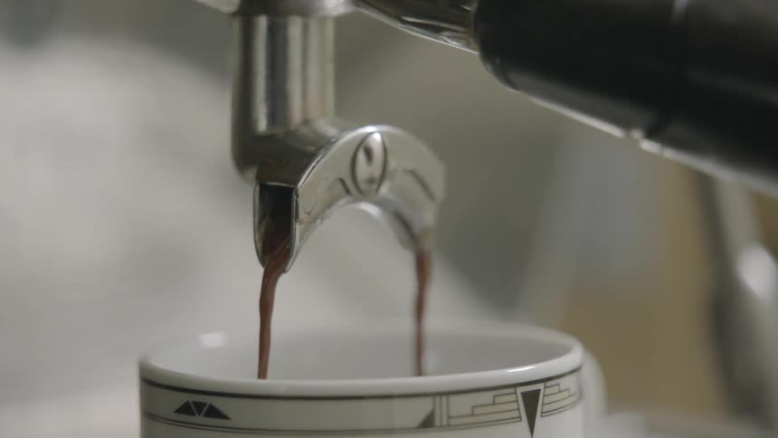 Coffee pours from a machine into a mug