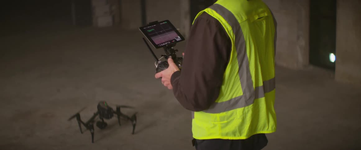 Person wearing safety vest manipulates drone with controller