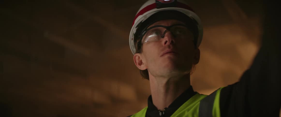 Laborer wearing safety vest and headlamp on his hard hat works