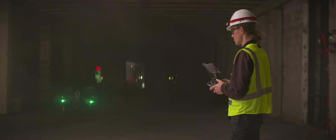 A man operates a radio controlled drone indoors at a construction site