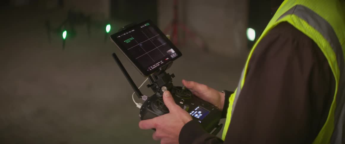 A man in a safety vest controls a drone