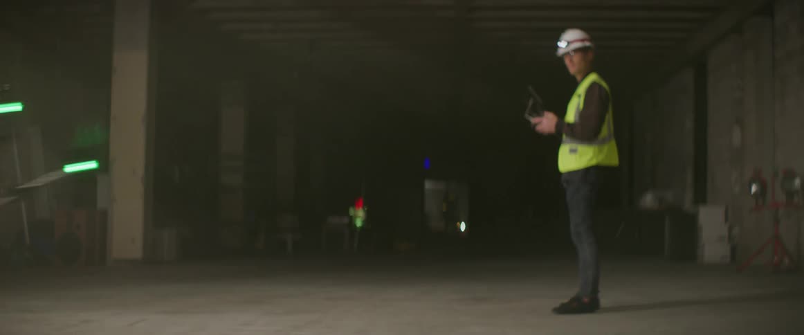 Worker wearing safety vest guides drone with controller