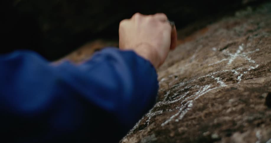 A mans hand drawing lines and stars with white chalk on trees and stone