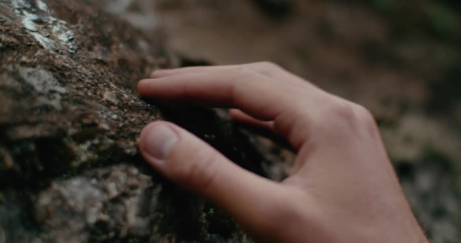 Person touches and strokes sloping rock with symbols drawn in chalk on the surface