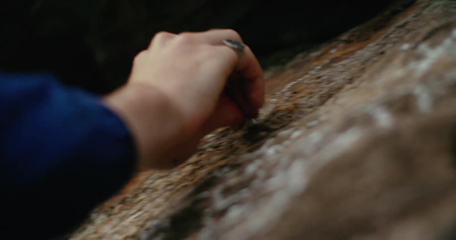 A man writes on the side of a cliff with chalk