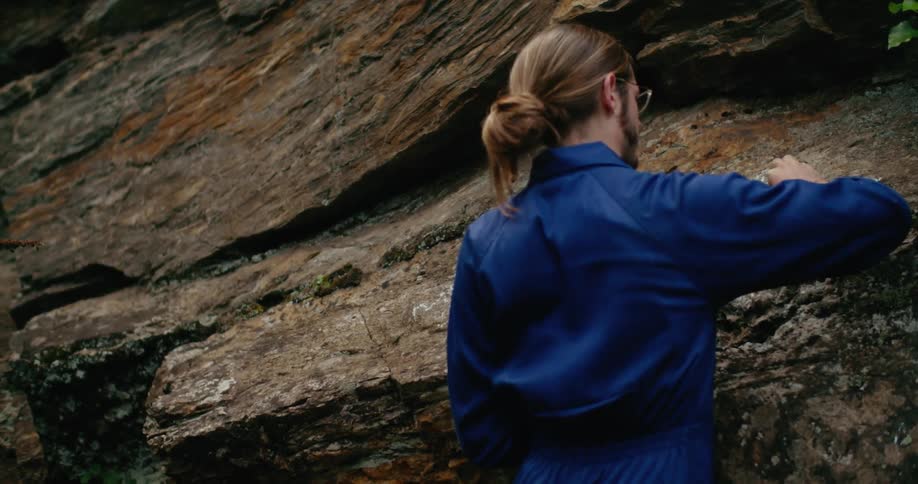 A man writes on the side of a cliff with chalk