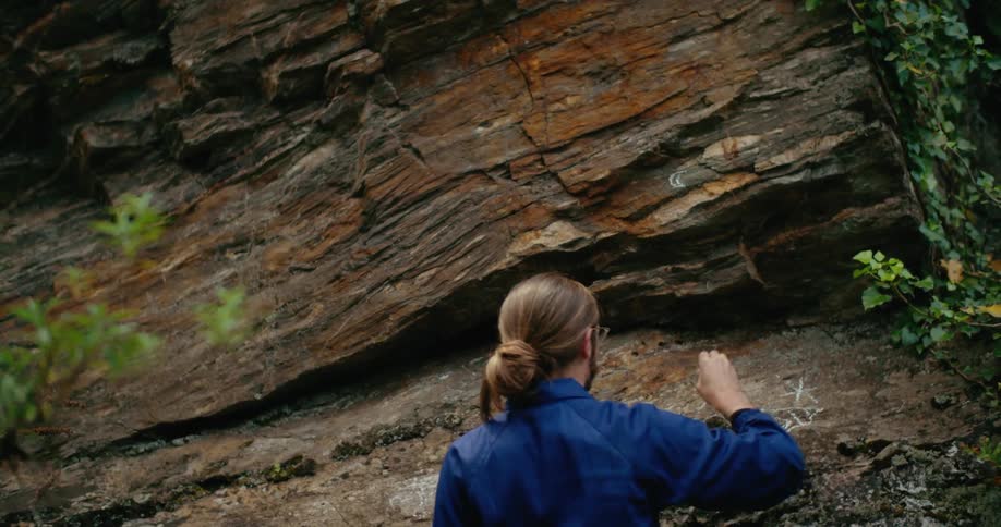 A man writes on the side of a canyon with chalk