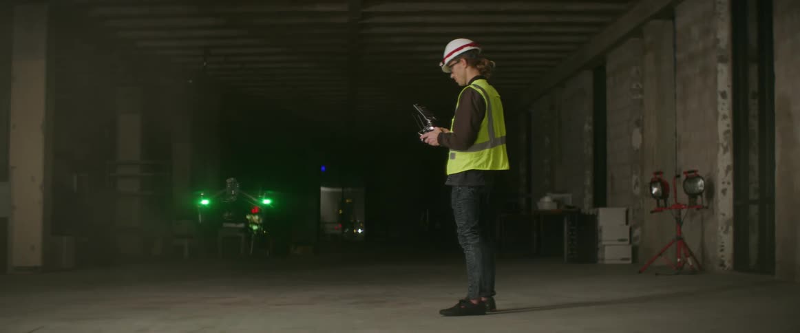 Worker wearing a safety vest and a hard hat practices with drone