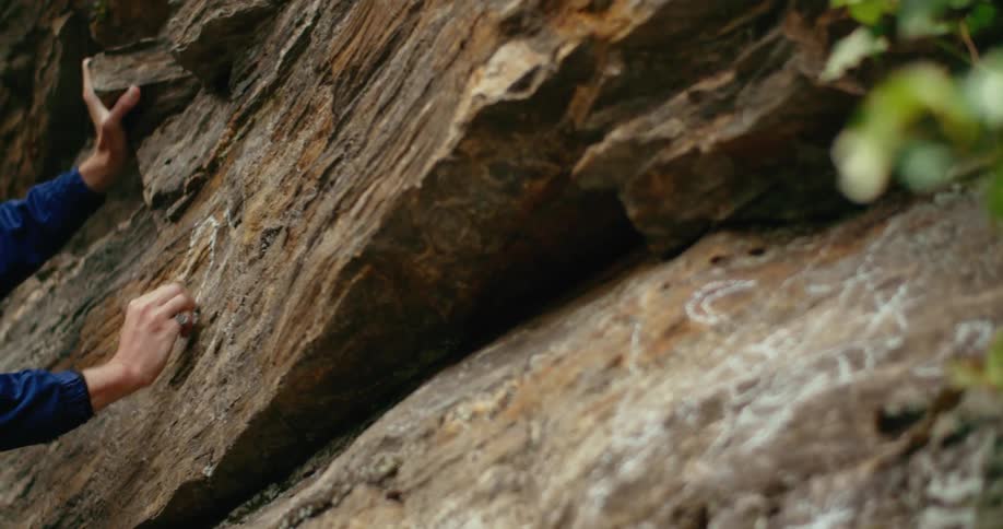 Person draws on inclined rock wall with chalk