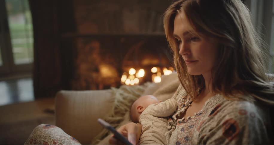 A woman holds her baby while using her cell phone
