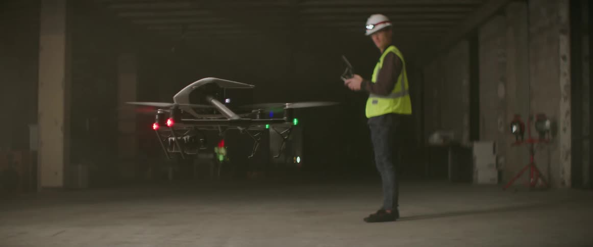 A man lands the drone in the building at night