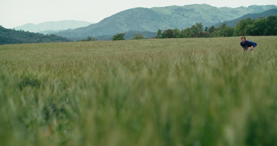 A man runs through a field as his dog chases him