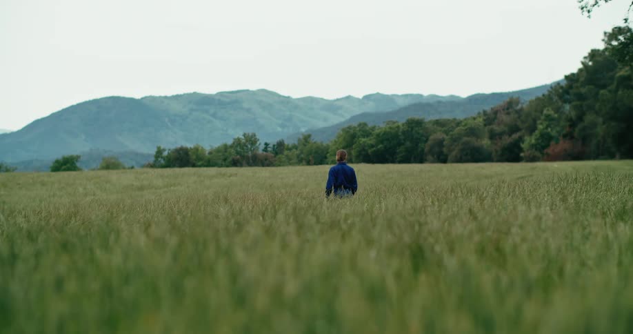A man stands in an open field and looks into the distance