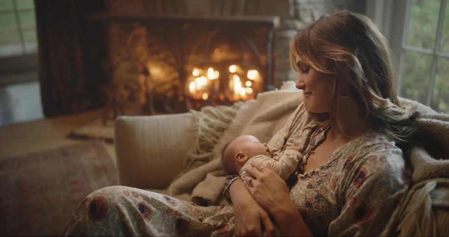 Mother cradles her baby on the couch