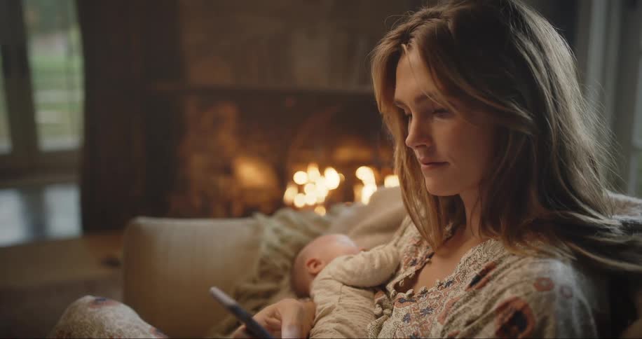 Mother sits by fire holding her newborn