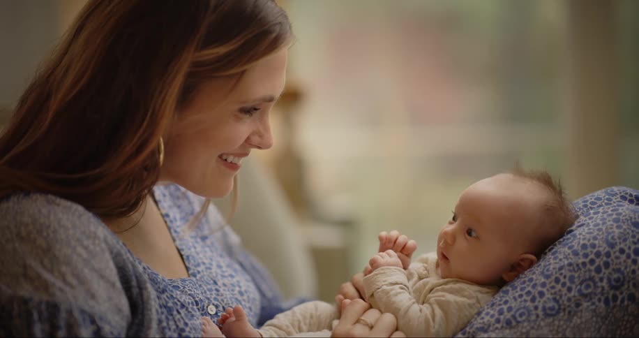 Mother at home with newborn baby in her lap