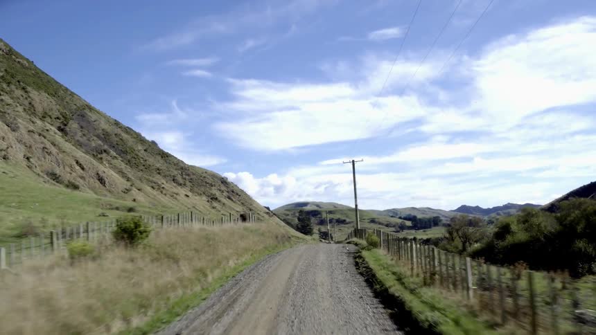 A dirt road between fences and a line of telephone poles
