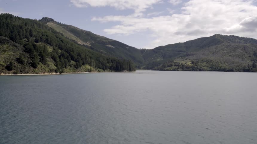 A tree covered mountain range is surrounded by water