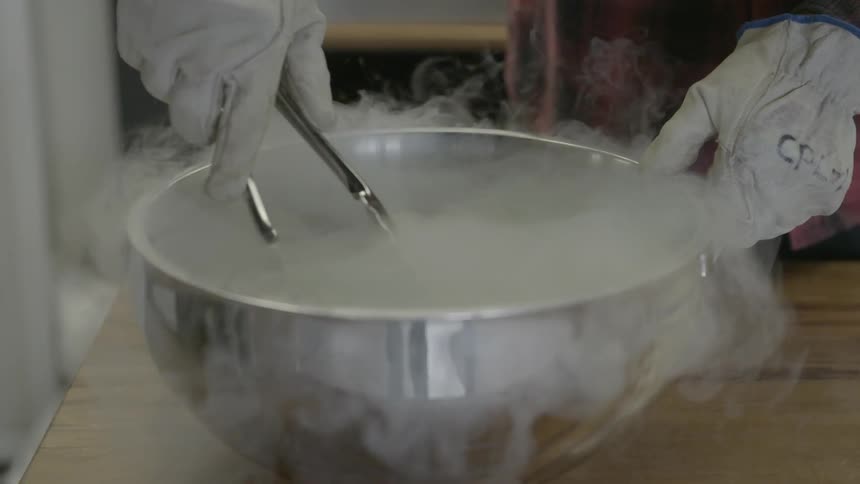 A person wearing gloves mixes in a metal bowl