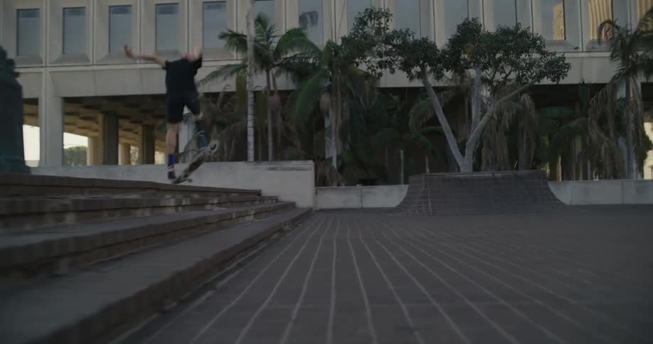 A man jumps down the steps on his skateboard and falls