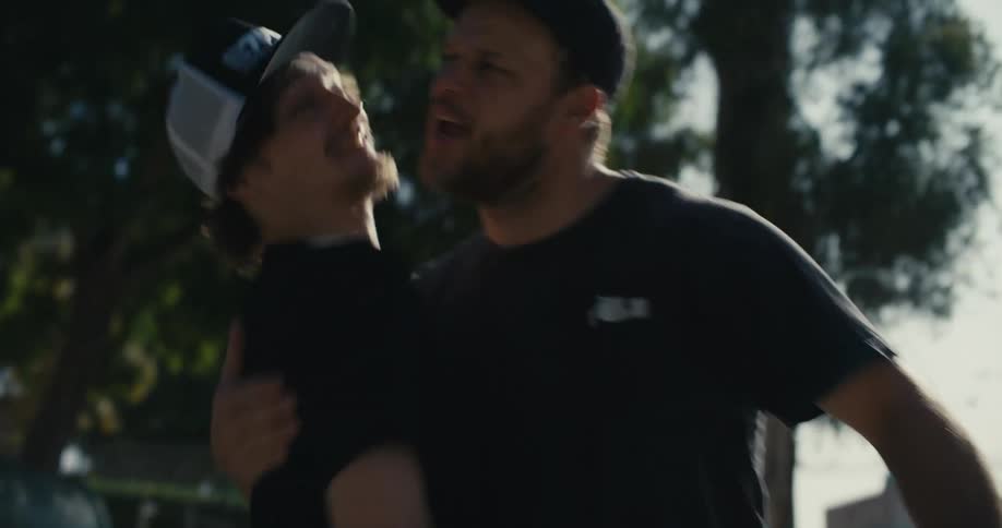 Two men high five and hug one another outside a building