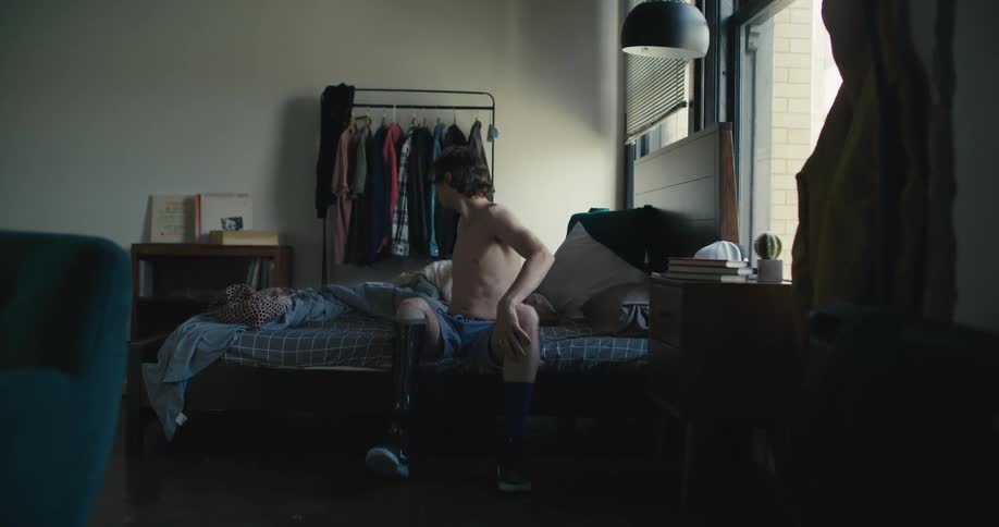 A man putting on shoes and a shirt
