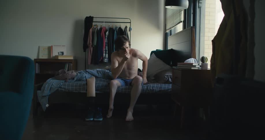 A man with a prosthetic leg gets out of bed and checks the time on his smartphone